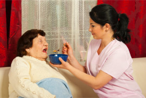 caregiver feeding the elderly woman
