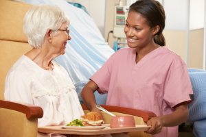 caregiver gives food to elderly woman