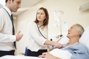 medical staff on rounds examining senior male patient